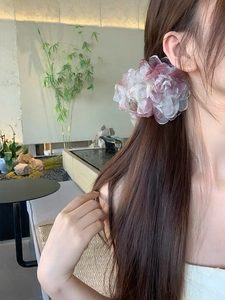 Vista dettagliata della pinza per capelli a fiore 3D in tessuto con petali rosa sfumati