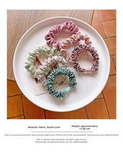 Close-up of five colorful elastic hair scrunchies with 5cm diameter in a white ceramic dish