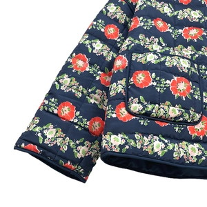 Detailed view of dark blue quilted floral jacket with red flowers and pocket stitching