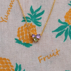 Collier cœur doré pour femme avec cristaux de zircon violets et verts sur tissu à imprimé fruit