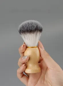 Detail of wooden handle shaving brush with soft synthetic bristles held by hand