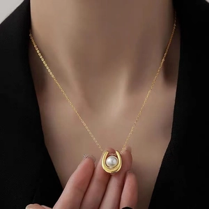 Elegant gold U-shape pendant necklace with white pearl on a woman's neck