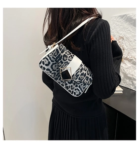 Detailed view of leopard print shoulder bag featuring white strap and square metal buckle