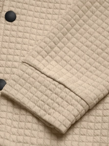 Detail shot of khaki quilted jacket featuring classic diamond patterns and black buttons