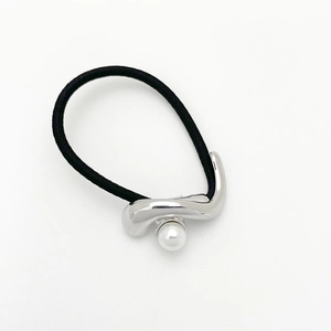 Dettaglio di un elastico nero con decoro in metallo argento e una perla bianca sintetica
