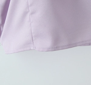 Gros plan sur la texture en polyester violet et les coutures de l'ourlet de la mini-robe