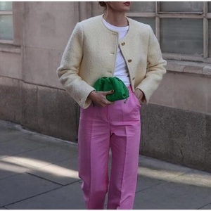 Dettaglio di elegante giacca in tweed beige con pantaloni rosa e borsa cloud verde