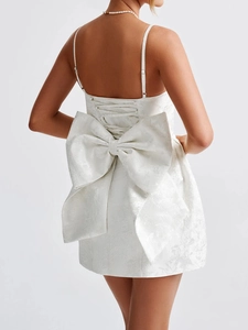 Detail view of white jacquard mini dress featuring a large bow and corset lace-up back