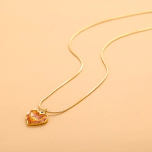 Close-up of golden snake chain with heart pendant featuring orange flame texture
