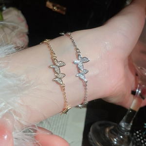 Detailed close-up of zircon butterfly bracelets in gold and silver on a soft sleeve