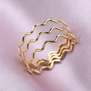 Close-up of triple-layered wavy gold ring on purple silk fabric background