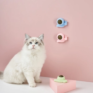 Adhesive snail catnip ball toy attached to wall with cat playing in pink background