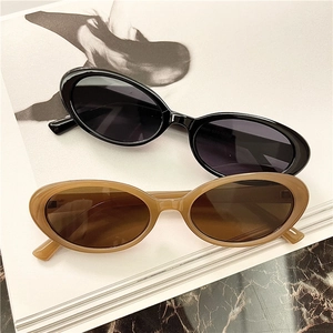 Detail showing classic black and amber tortoise oval sunglasses on a fashion magazine