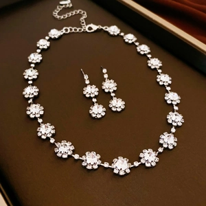 Détail d'une parure de bijoux fleur en argent avec strass scintillants et un collier