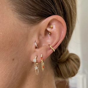 Detailed view of gold S925 silver earrings with tassels, orange gems and white zircons
