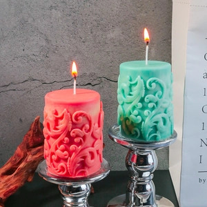 Vela cilíndrica con relieve floral en soporte plateado en coral y verde menta