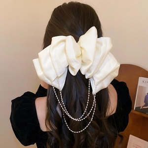 Detail of cream satin bow hair clip with faux pearl fringe on model hairstyle