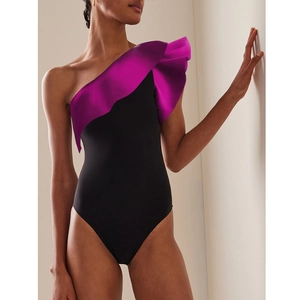 Detail of one-shoulder ruffles in purple contrast on black slimming swimsuit