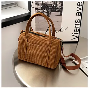 Detailed close-up of brown corduroy Boston bag with double handles and shoulder strap