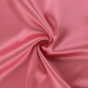 Macro shot of pink satin fabric texture with spiral folding and elegant silky luster