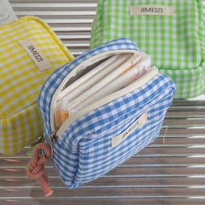 Internal view of a plaid fabric pouch showing practical storage for hygiene products