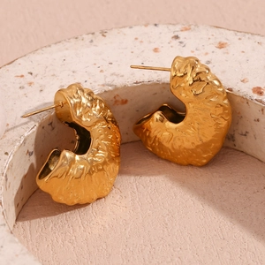 Detailed macro view of 18K gold plated fan-shaped earrings with hammered metal texture