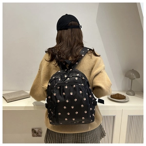 Black nylon floral backpack with pink flowers shown on model in a cozy interior setting