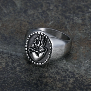 Close-up of gothic stainless steel ring with flame sacred heart relief on stone surface