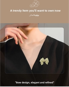 Close-up of a champagne gold bow brooch with white pearls pinned on a black garment