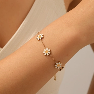 Chic gold stainless steel bracelet featuring three white and yellow enamel daisy charms