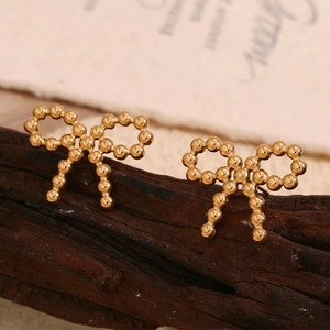 Detail of 18K gold plated bow earrings with bead texture on dark wood background