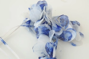 Détail d'une robe fleurie bleue et blanche en mousseline avec col en V et jupe pétale