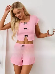 Détail d'un ensemble pyjama rose côtelé avec petits nœuds en satin noir et col carré