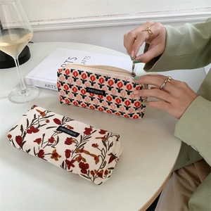Vintage corduroy makeup pouch with tulip and floral embroidery on a white table