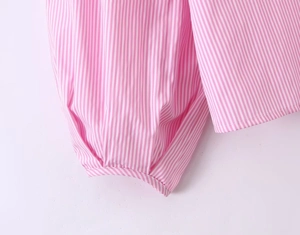 Dettaglio del tessuto a righe rosa e bianche con polsini elastici e pieghe raffinate
