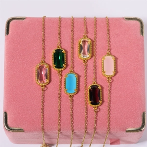 Macro view of six multicolored oval gemstones in gold plated bezel pendant settings