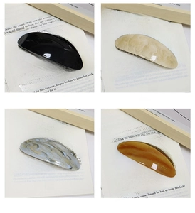Detailed set of four acetate hair clips in black, marble, blue, and amber colors