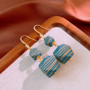 Detailed close-up of retro teal geometric bead earrings with golden stripes and zircons
