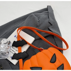Detail of pumpkin crossbody bag with black bat wings and textured orange PU leather