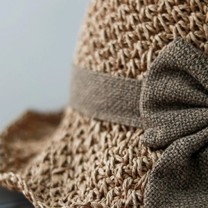 Women's summer straw hat with brown linen bow decoration in natural light brown tone