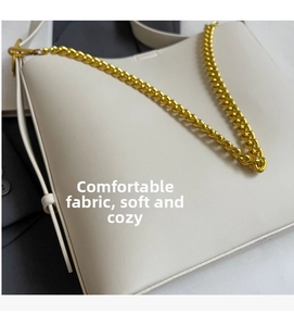 Close-up of white crossbody bag featuring soft leather texture and gold chain strap detail