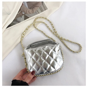 Detail of silver quilted crossbody bag with glossy finish and gold chain strap