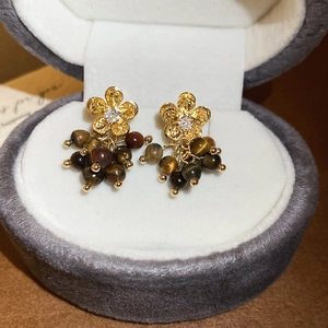Dettaglio di orecchini a fiore con perle occhio di tigre e zircone bianco su velluto