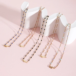 Close-up of golden Ankh cross necklaces with colorful beads on a white wave display stand