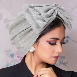 Detail of silver sparkling turban hat with a large bow showing fabric texture and craftsmanship