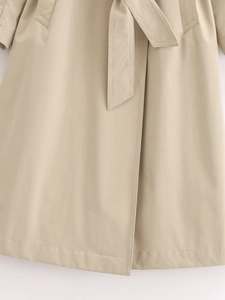 Close-up of beige trench coat featuring adjustable belt and premium stitching details