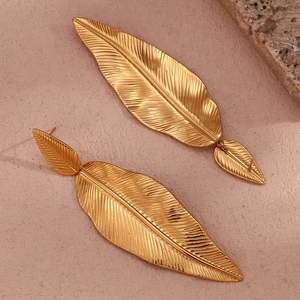 Macro detail of 18K gold-plated feather leaf earrings showing intricate metal textures