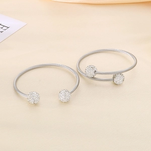 Close-up of silver steel wire bangles with sparkling full-diamond beads on satin