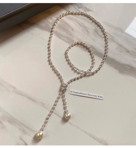 Detailed view of elegant Y-shaped pearl necklace with zircon spacers on marble background