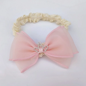Detail of pink chiffon bow baby headband with rhinestone crown on beige lace band